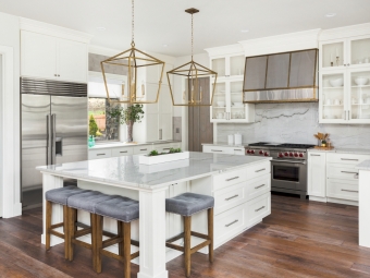 Beautiful white kitchen in new luxury home. Features large island,pendant lights, and hardwood floors